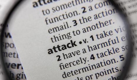 A dictionary as the starting point for a cyberattack In a dictionary, under the initial letter A, the term attack, which symbolizes cyber-attacks, is shown enlarged by a magnifying glass.