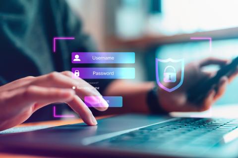 Person gibt auf einem Notebook ein Passwort ein (etwas, das man weiß), was durch eine virtuelle darüberliegende Eingabemaske symbolisiert wird.