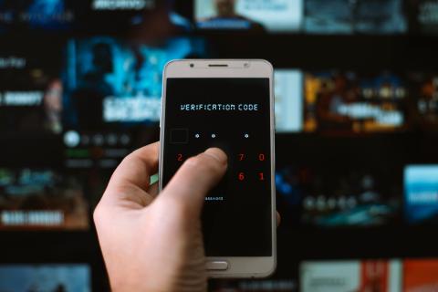 User is logging in on smart-TV in the background by entering a verification code in his smartphone