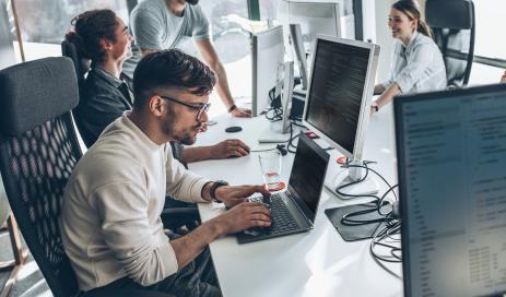 Der technische Datenschutz wird von einer Gruppe von Programmierern und Softwareentwicklern sichergestellt, die vor ihren Bildschirmen sitzen und den Code bewerten.