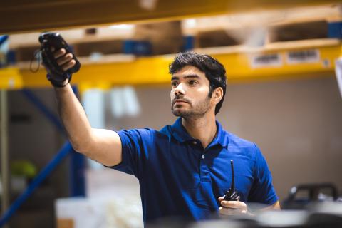 Warehouse worker logged in SaaS solution on their handheld computer to check newly arrived goods in the warehouse.