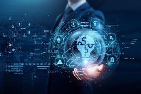 A businessman holds a hologram in his hand that shows a lamp made of puzzle pieces and is supposed to represent complex operations.