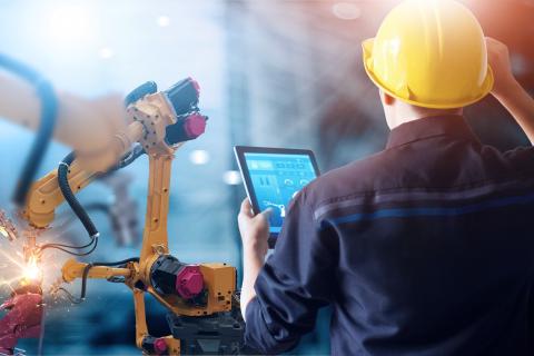 Worker is registering himself at a tablet to start engineering check of a robotics arm machine.